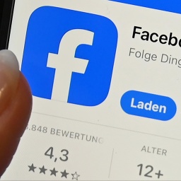 Symbolbild, Nahaufnahme eines Smartphone-Bildschirms. Ein Finger zeigt auf das Facebook-Logo.