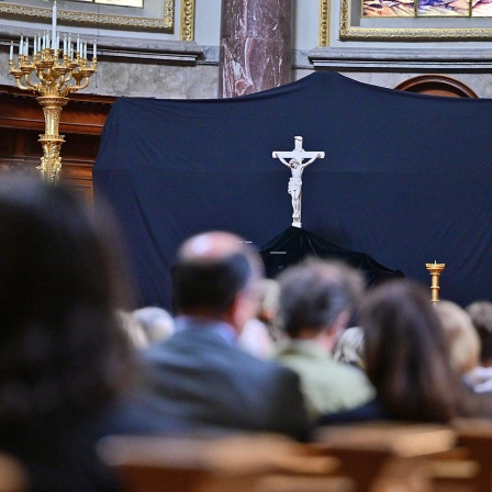 Besucher sitzen beim Karfreitagsgottesdienst vor dem verhüllten Altar im Berliner Dom.