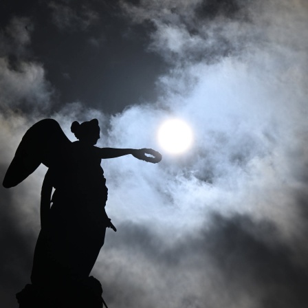 Sonne und dunkle Wolken stehen über der Jubiläumssäule mit der römischen Göttin Concordia auf dem Schlossplatz am Himmel.