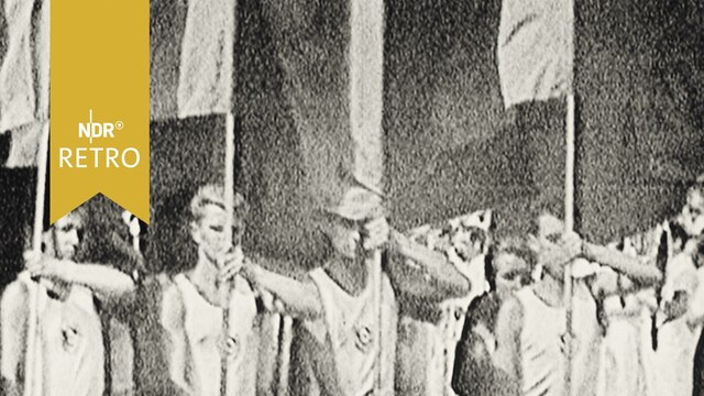Junge Sportler tragen heroisch Fahnen bei einer Parade (DDR 1964)