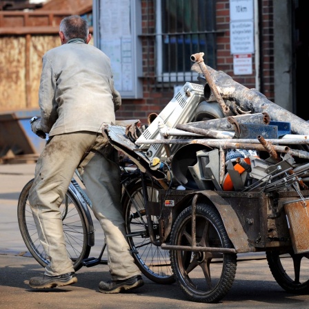 Ein Schrottsammler bringt auf einem Anhänger an einem alten Fahrrad gesammeltes Altmetall auf den Hof eines Schrottverwerters. 