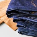 Ein Stapel Jeans neben einer Einkaufstüte aus Papier: Ein Unternehmen rückverlagert seine Jeans-Produktion wieder nach Deutschland.