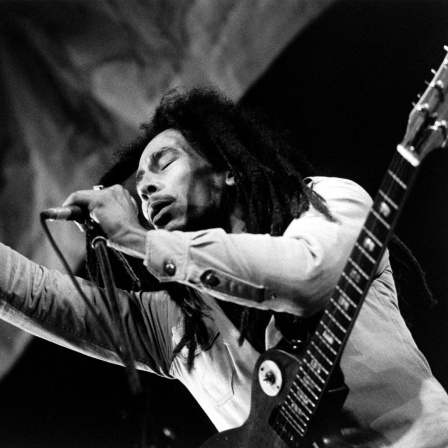 Schwarz-weiß-Foto von Bob Marley auf der Bühne mit geschlossenen Augen.