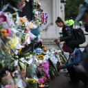 Am Buckingham Palace in London haben zahlreiche Menschen als Zeichen ihrer Trauer um Queen Elizabeth II. Blumen niedergelegt. Eine Frau kniet davor.
