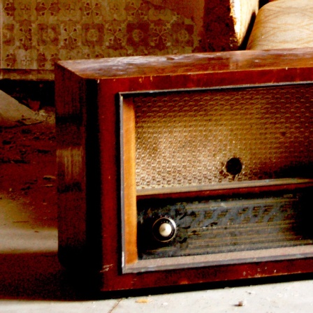 Ein altes Radio steht vor einem alten Sofa. 