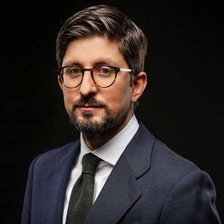 Politikwissenschaftler Prof. Rafael Bauschke trägt einen Anzug, steht vor einem dunklen Hintergrund und schaut in die Kamera. In SWR1 Leute analysiert er die Wahl in Bayern und Hessen: Was bedeuten die Ergebnisse für Deutschland und unsere Demokratie?