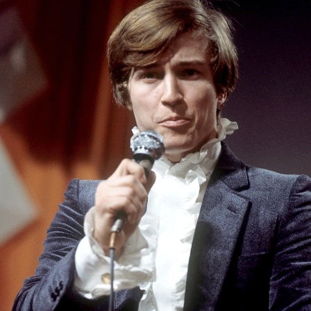 Christian Anders 1970 mit Mikrofon und Rüschenbluse auf der Bühne.