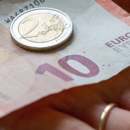 Eine Person hält 12 Euro in der Hand.