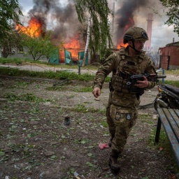 Ein Polizist läuft vor einem brennenden Haus, das durch einen russischen Luftangriff zerstört wurde.