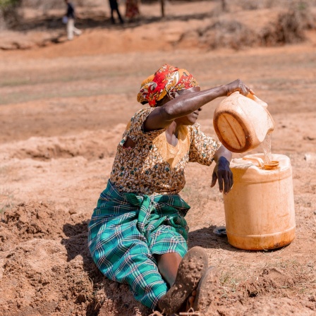 African woman fetching water in dry area with a yellow Jerrycan - East Africa xkwx East
