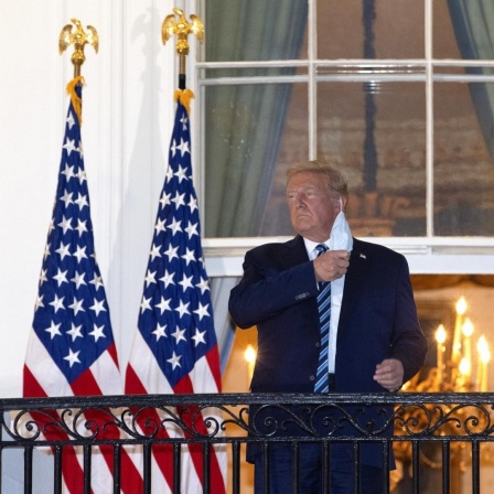 Präsident Trump steht auf dem Balkon am Weißen Haus und nimmt seine Schutzmaske ab