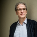 Autor Dirk Oschmann mit kurzen gruan Locken und einer Brille.