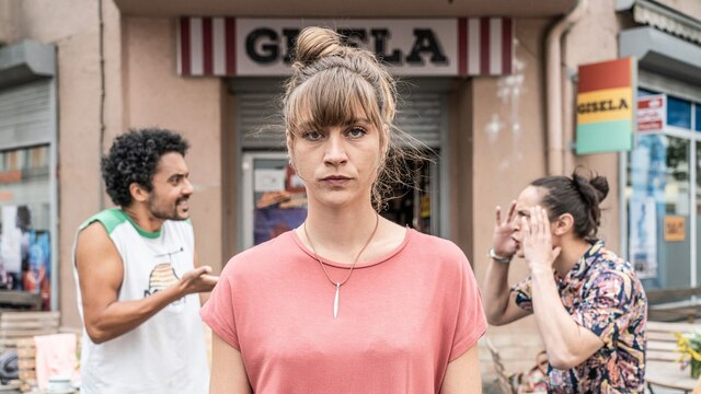 Sandra (Sophie Pfennigstorf) steht vor einem Leipziger Spätverkauf. Im Hintergrund ihre beiden Partner Jerome (Omar El-Saeidi) und Tom (Madieu Ulbrich).