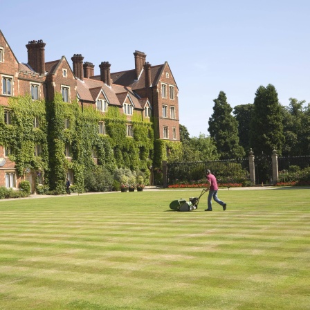 Mann mäht Rasen im Innenhof des Selwyn College, Universität Cambridge, England