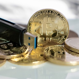 Bitcoin.Goldmünzen neben USB Stick Wallet. 