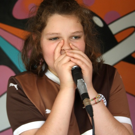 Ein Junge umfasst ein Mikrofon eng am Mund, um zu beatboxen.