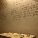 Kerzen brennen im Gedenkraum vor dem in die Wand eingravierten Lied der Moorsoldaten