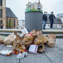 Müll liegt in der Innenstadt neben einem überfüllten Abfallbehälter