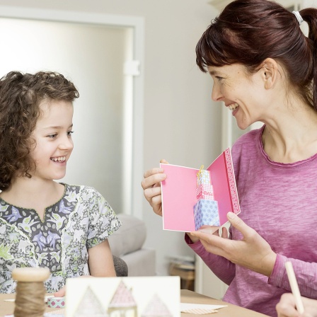 Kinder übereichen einer Frau ein Geschenk.