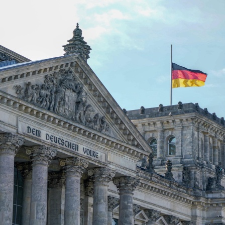 Reichstag in Berlin - Deutscher Bundestag mit Deutschlandflagge.