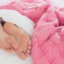 Füße gucken unter einer Bettdecke hervor