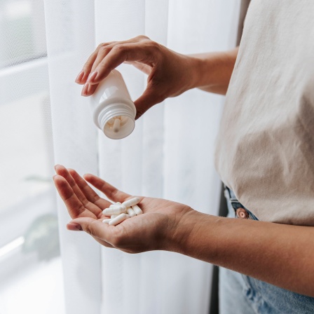 Frau schüttet sich Tabletten auf die Hand