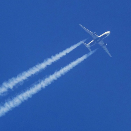 Ein Flugzeug hinterlässt Kondensstreifen am Himmel.