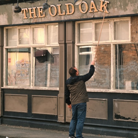 Ein Mann repariert den Schriftzug "The Old Oak" über einem Pub