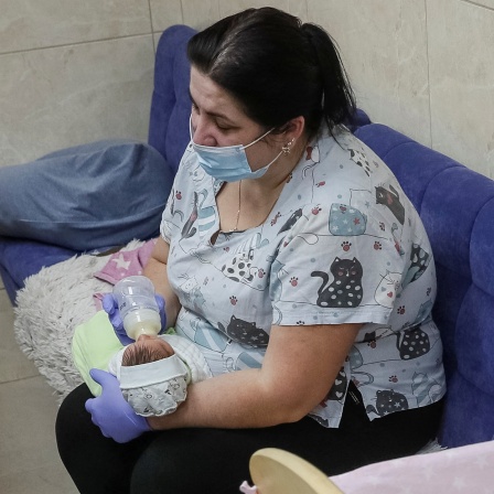 Eine Frau gibt einem Baby die Flasche, das von einer Leihmutter geboren wurde