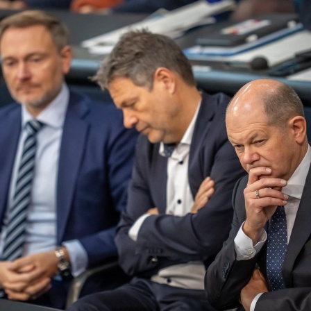 Bundeskanzler Olaf Scholz (SPD, r), verfolgt neben Robert Habeck (Bündnis 90/Die Grünen, M), Bundesminister für Wirtschaft und Klimaschutz, und Christian Lindner (FDP), Bundesminister der Finanzen, die Debatte nach einer Regierungserklärung zur Haushaltslage im Bundestag.