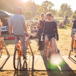 Festivalbesucher vom Futur 2 strampeln auf Fahrrädern. 