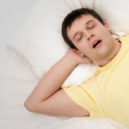 Mann schläft mit offenem Mund in einem Bett