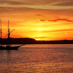Kieler Förde bei Sonnenuntergang. Ein Segelschiff fährt gerade wieder ein.