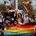 Mehrere junge Leute halten Fahnen, die die Transgender-Community repräsentieren