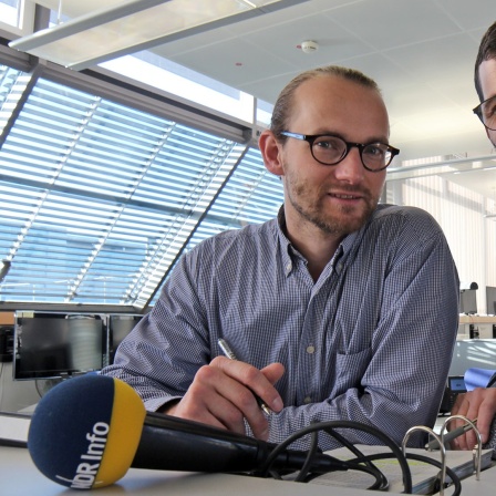 Benedikt Strunz und Philipp Eckstein stehen mit Unterlagen am Tisch