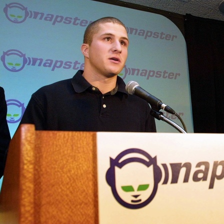 Der Gründer der Musiktauschbörse Napster, Shawn Fanning, am Mikrofon. Am Pult und im Hintergrund das Napster-Logo