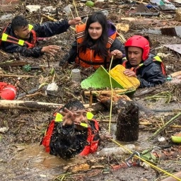 Menschen mit Rettungsschwimmwesten stehen in einer überfluteten Straße in Kathmandu, Nepal 