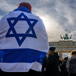 Ein Demonstrant trägt die israelische Nationalflagge auf dem Rücken bei einer Protestkundgebung gegen die umstrittene Justizreform in Israel vor dem Brandenburger Tor, 27. März 2023