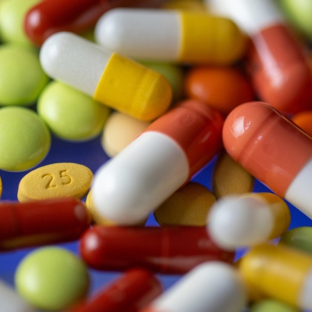 Wild verstreut lieben unterschiedliche, bunte Tabletten und Kapseln auf einem Tisch.