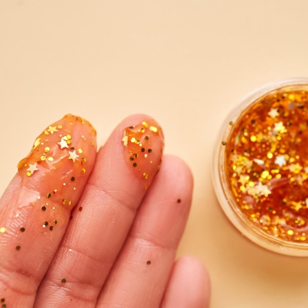 Finger mit goldendem Glitter aus einem Töpfchen