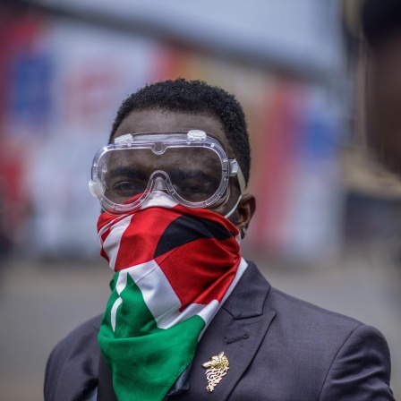 Ein Demonstrant trägt eine Schutzbrille und eine kenianische Flagge vor Mund und Nase.