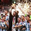 Kapitän Lionel Messi reckt bei der Siegesfeier mit der argentinischen Mannschaft den goldenen Pokal im Lusail Iconic Stadium nach oben