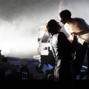 Auf einer Bühne auf der sich Steine staplen stehen zwei Personen, ihre Gesichter zueinander geneigt als würden sie sich gleich küssen.
