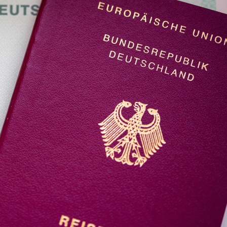 Eine Einbürgerungsurkunde der Bundesrepublik Deutschland (l) und ein deutscher Reisepass liegen auf einem Tisch