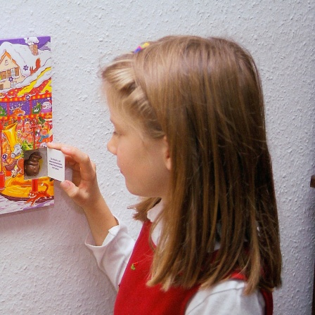 Ein Mädchen öffnet ein Türchen an einem Adventskalender