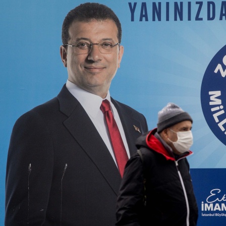 Archivbild: Eine Person geht an einem Plakat von Ekrem İmamoğlu vorbei.