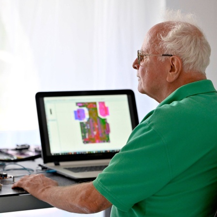 Ein Senior arbeitet in seiner Elektronik-Werkstatt im Home-Office