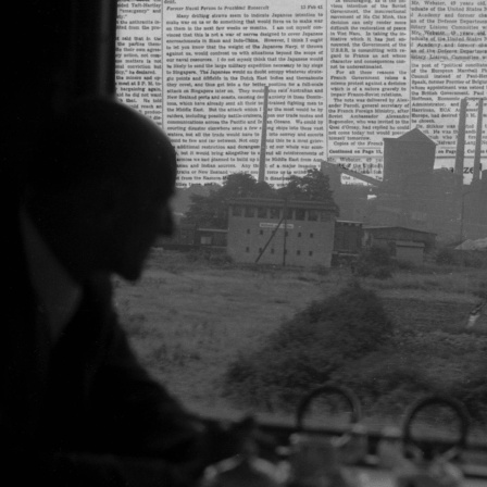 Mann, der im Zug sitz und auf Landschaft mit Buchstabenhimmel guckt.