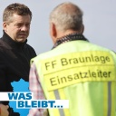 Ein mittelatler Mann mit dunklen Haaren guckt einen Mann mit neongelber Warnweste an, die die Aufschrift "FF Braunlage Einsatzleiter" trägt.
