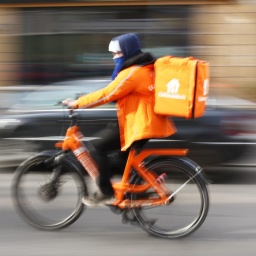 Ein Fahrer von Lieferando fährt auf seinem Rad in Berlin im Bezirk Mitte auf der Friedrichstraße